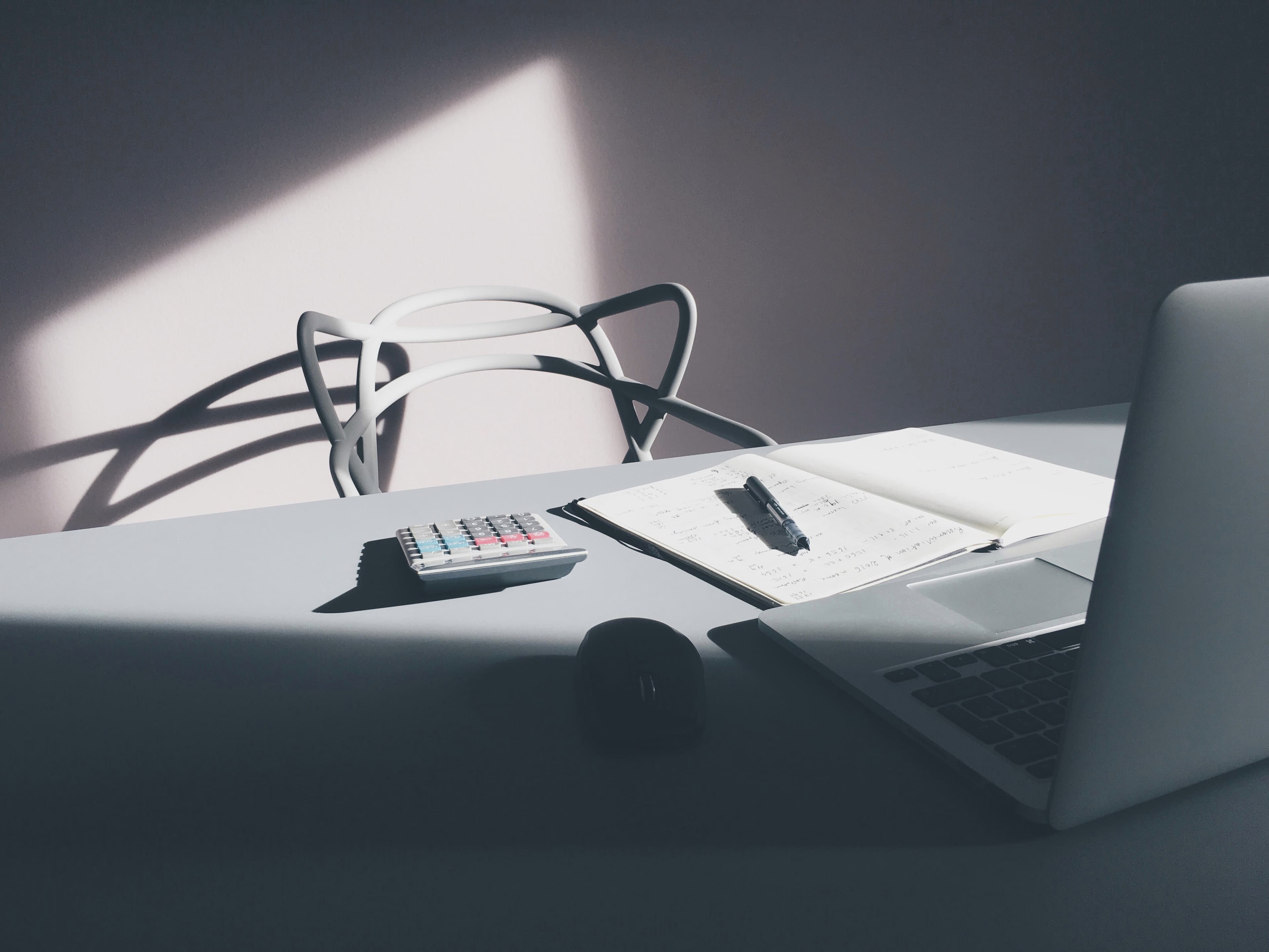 A laptop, notebook, and calculator representing AI coding cost planning